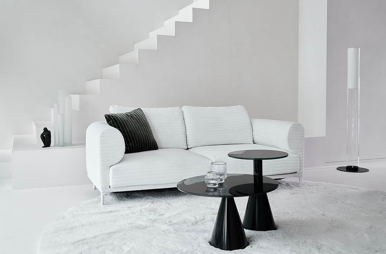Weißes Sofa mit weich abgerundeten Armlehnen, zwei großzügigen Sitzpolstern und ruhiger in heller Wohnumgebung.